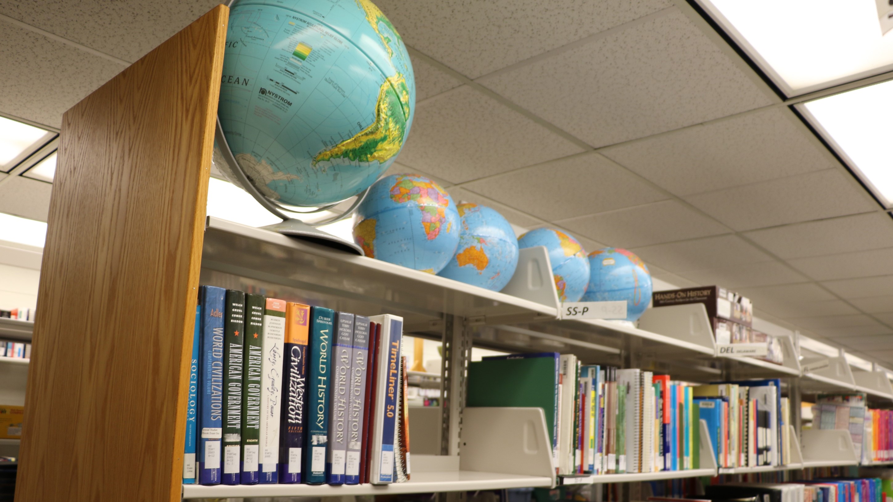 This image shows a row of resources at the Educational Resource Center, which include globes and World History reference books.