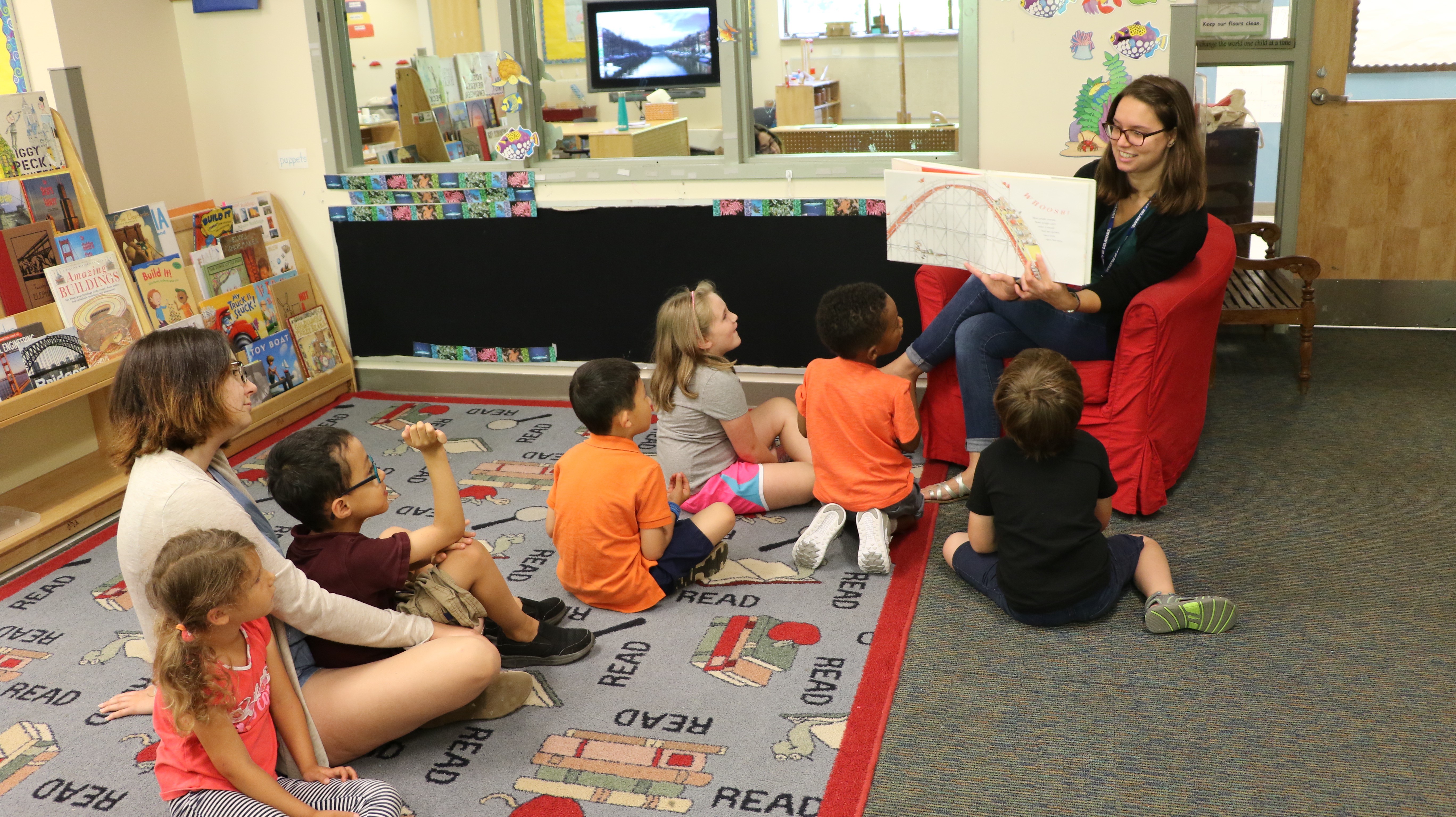 A student teacher reads aloud to a group of young children at CEHD's children's campus..