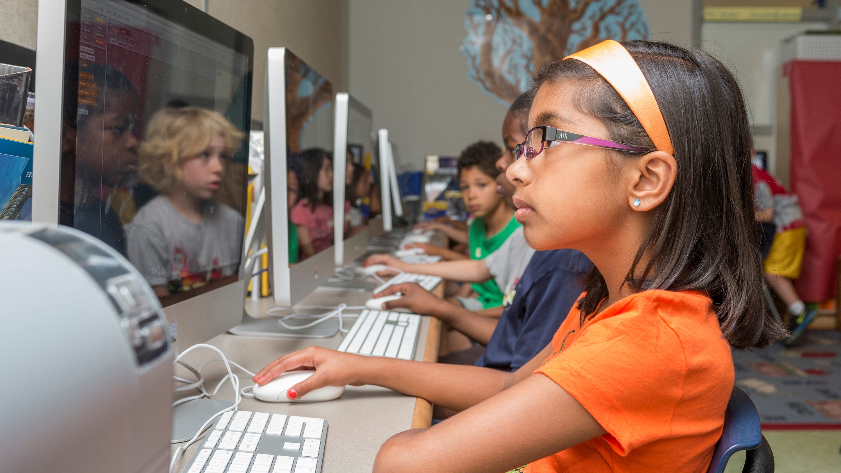 A young girl uses a computer during a classroom activity.