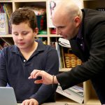 A UD professor works with a child on a classroom activity using laptops on CEHD's Children's Campus.