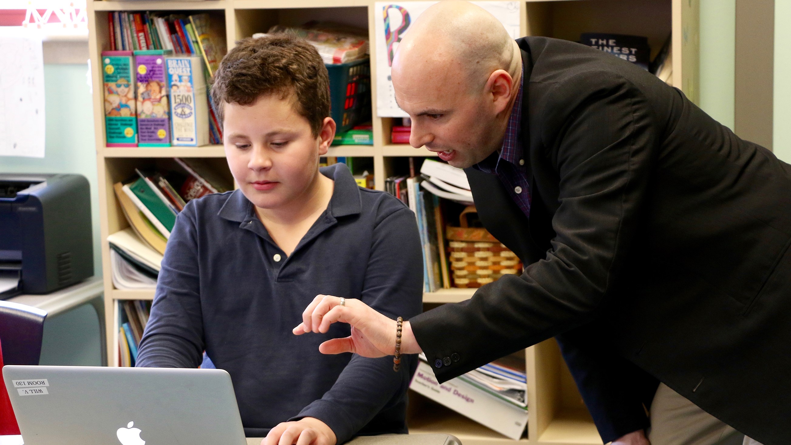 A UD professor works with a child on a classroom activity using laptops on CEHD's Children's Campus.