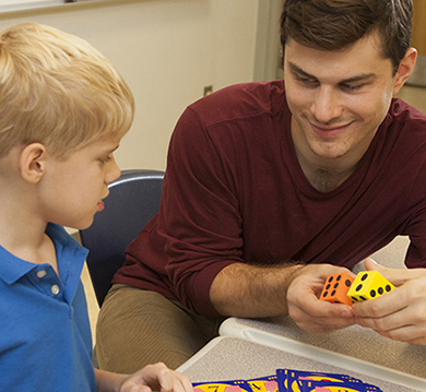 Teacher shows dice to a child as part of a math lesson