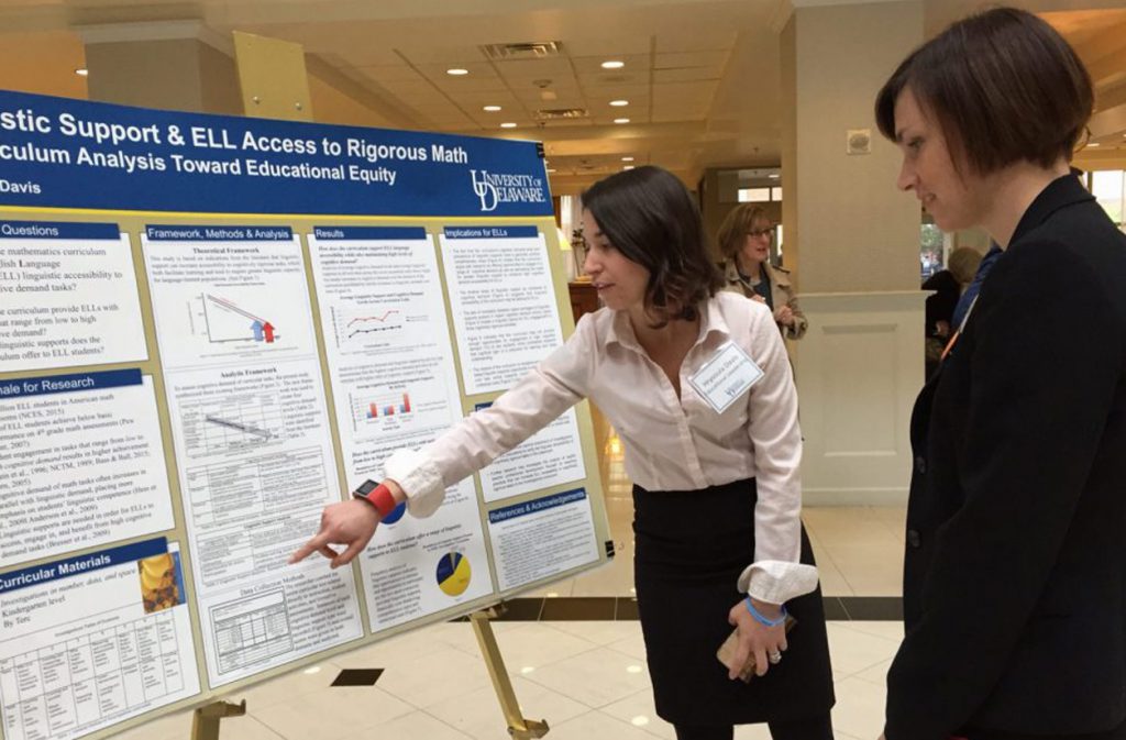 Doctoral student shows her research poster to a woman