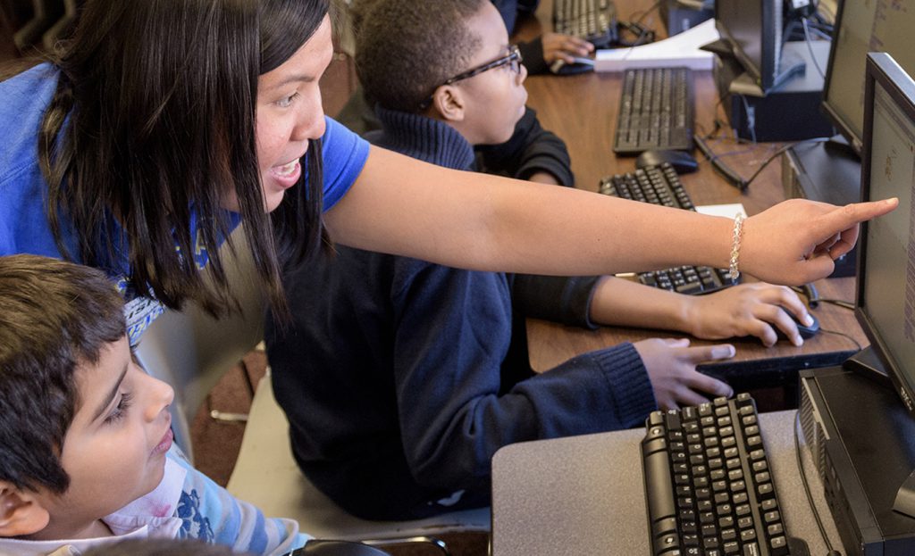 Teacher points to computer while teaching students