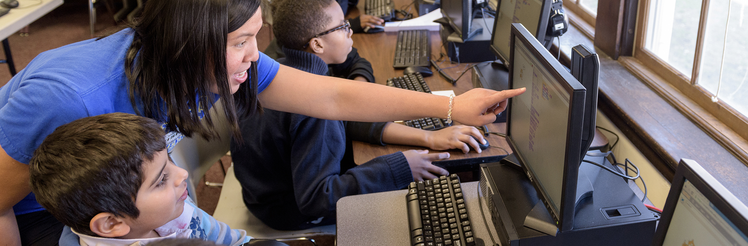 Teacher points to computer while teaching students