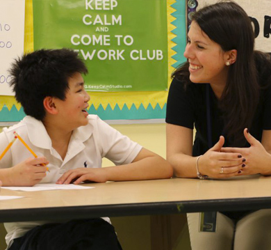 A doctoral student smiles at a boy in a classroom