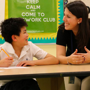 An Exceptional Children and Youth student talks with children with disabilities around a long table.