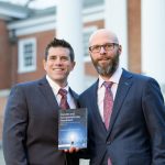 This image shows UD alumni Joseph Jones and T.J. Vari, administrators in the New Castle County Vocational Technical School District and Appoquinimink School District, respectively, with their new book on UD's campus. Their new book, Candid and Compassionate Feedback, is available through Routledge.