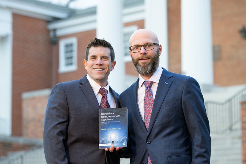 This image shows UD alumni Joseph Jones and T.J. Vari, administrators in the New Castle County Vocational Technical School District and Appoquinimink School District, respectively, with their new book on UD's campus. Their new book, Candid and Compassionate Feedback, is available through Routledge.