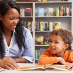 A staff member in UD Center for Research Use in Education reads books with a child in the reading room of UD's Education Resource Center.