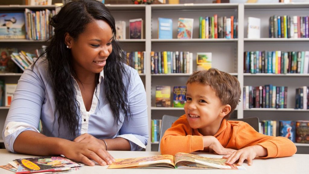 A staff member in UD Center for Research Use in Education reads books with a child in the reading room of UD's Education Resource Center.