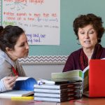 A teacher works with a member of UD's Professional Development Center for Educators at a table in her classroom.