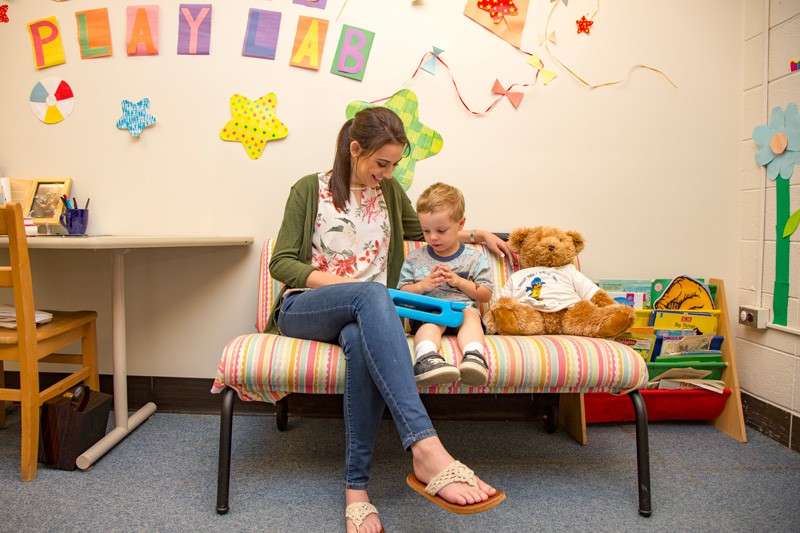 Hillary May, who was crowned Miss Delaware 2019, is a graduate research assistant at the University of Delaware in the Child’s Play, Learning, and Development Lab, where she studies how toddlers develop language skills. She plays with a child on a couch in UD's Child's Play, Learning and Development Lab.