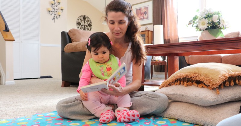 A mother enjoying quality time reading to her infant.