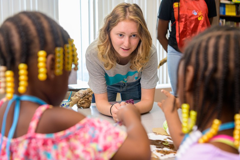 UD student Ashley Warokomski shows students at West End Neighborhood House how to make “slime” using glue, glitter and other materials, as they experiment with how varying the ratio of ingredients changes the result.