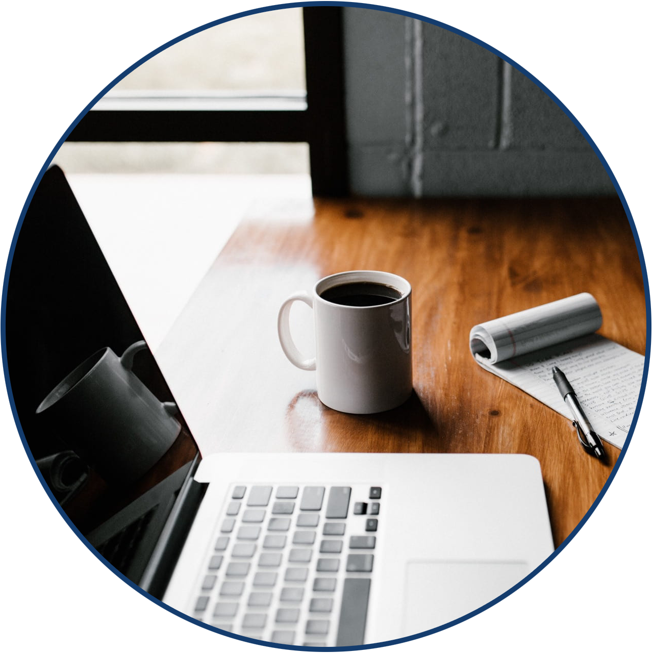 Laptop, coffee cup, notebook and pen on a desk