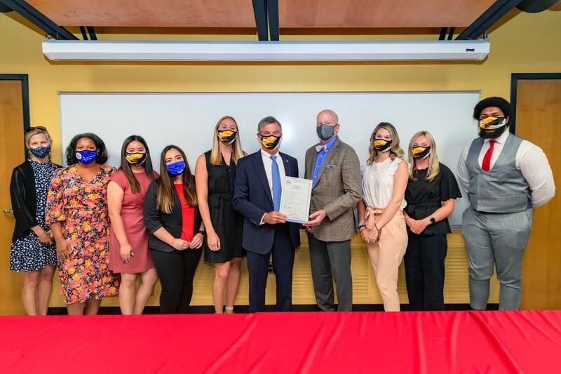 UD teacher residents accept teaching positions in Red Clay Consolidated School District during its Teacher Signing Day. From left to right: Krissy Najera (director of DCTE), Jamie Bailey (director of UD’s Teacher Residency program), Mariela Lomeli, Alexa Cruz, Meghan Purcell (UD residents), Governor John Carney, CEHD dean Gary T. Henry, Meghan Salter, Claire Bennett, and Clark Scott (UD residents).